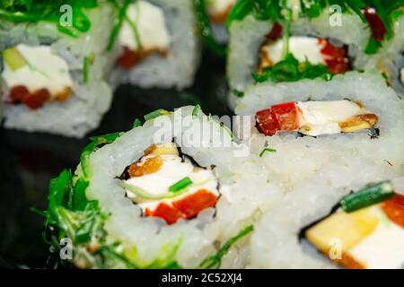 Petits pains avec du poisson, du fromage et des algues vertes. Un plat traditionnel japonais. Gros plan Banque D'Images