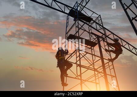 Silhouette de deux ouvriers de construction grimpant des échafaudages, Thaïlande Banque D'Images