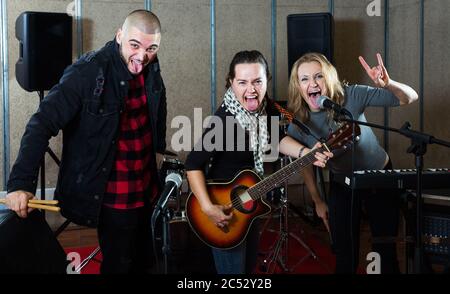 Groupe d'adultes expressifs de musiciens de rock posant avec des instruments dans un studio d'enregistrement Banque D'Images