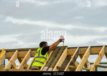 Porthcawl, pays de Galles - juin 2018 : ouvrier de la construction utilisant une perceuse à main pour fixer les vis dans la structure de toit d'un bâtiment en cours de rénovation Banque D'Images