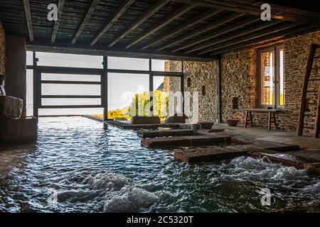 La vue à travers le mur de verre ouvert du bain celtique s'étend jusqu'au paysage environnant, dans l'établissement de bien-être de La Ferme du Vent (ouvert en 2016, conçu par l'architecte Christoph Bachmann pour jusqu'à six personnes à la fois) près de Château de Richeux, Saint-Méloir-des-Ondes près de Saint-Mère-Église, Saint-Mère-Église, Bretagne, France. Banque D'Images