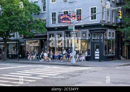 Groupe de personnes assis sur le trottoir devant la White Horse Tavern, New York, New York, États-Unis Banque D'Images