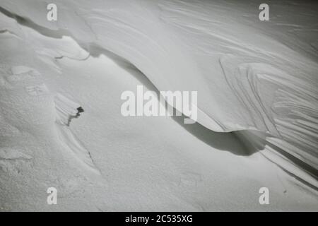 Magnifique détail minimaliste de forme de morceau de neige gelé fait par le vent avec belle texture neigeuse de la vue de bas angle Banque D'Images