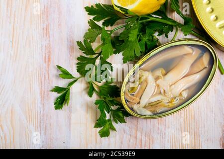 Fruits de mer. Palourdes d'eau salée ensis en boîte ouverte sur table en bois avec citron et verts Banque D'Images