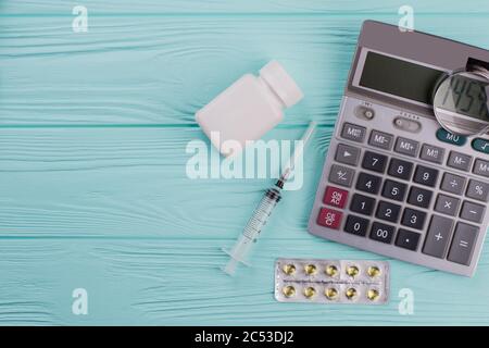 Loupe sur calculatrice et divers médicaments médicaux. Banque D'Images