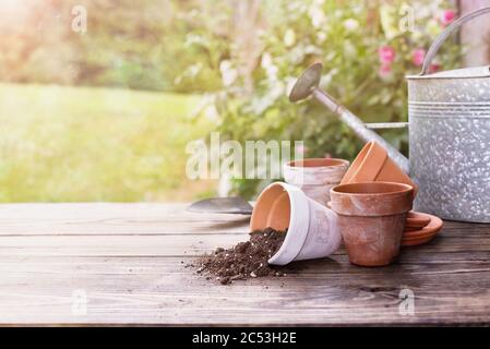 Pots en terre cuite et terre sur un banc de jardinage à l'extérieur, par une belle journée d'été. Profondeur de champ extrême et peu profonde avec mise au point sélective sur le centre de la table et Banque D'Images