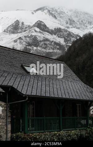 Maison classique en bois au milieu d'une montagne enneigée par une journée très nuageux. Banque D'Images