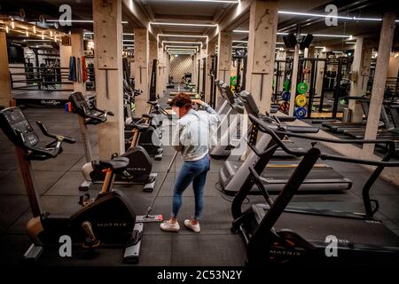 Un travailleur d'une salle de gym est vu porter un masque facial pendant le nettoyage du sol de la salle de gym en raison de la crise du coronavirus. Des ajustements de distance sociale d'un mètre et demi sont effectués à l'aide de bandes et de vaporisateurs de désinfection mis à disposition pour une utilisation individuelle au Vondelgym Gym à Amsterdam après le rapport que les clubs sportifs peuvent rouvrir à partir du 1er juillet. Banque D'Images