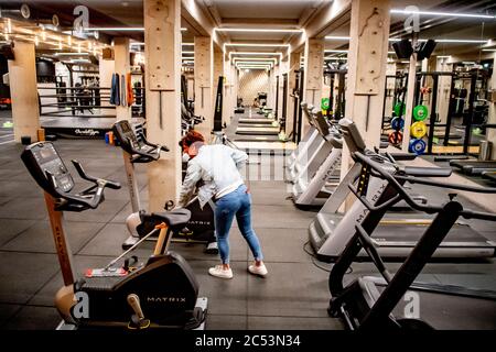 Un travailleur d'une salle de gym est vu porter un masque facial pendant le nettoyage du sol de la salle de gym en raison de la crise du coronavirus. Des ajustements de distance sociale d'un mètre et demi sont effectués à l'aide de bandes et de vaporisateurs de désinfection mis à disposition pour une utilisation individuelle au Vondelgym Gym à Amsterdam après le rapport que les clubs sportifs peuvent rouvrir à partir du 1er juillet. Banque D'Images