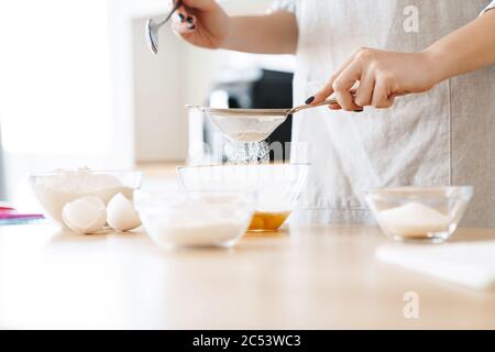 Image rognée d'une jeune femme caucasienne préparant de la pâte tout en cuisinant du gâteau dans une cuisine moderne Banque D'Images