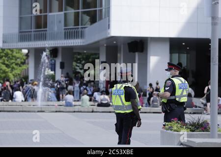 Deux policiers observent les gens qui se rassemblent pour une manifestation pacifique contre le racisme à l'hôtel de ville de Hamilton, Ontario Canada Banque D'Images