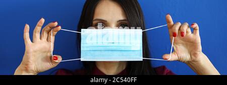 Belle femme tenant dans les mains masque de protection bleu l'mettant sur Banque D'Images