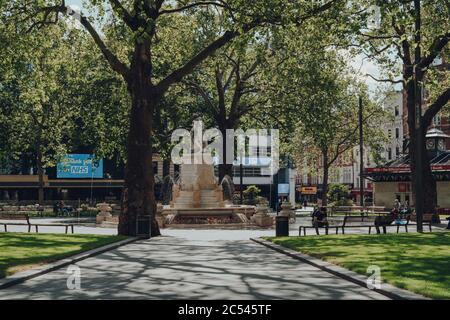 Londres, Royaume-Uni - 13 juin 2020 : peu de personnes se détendent sur un banc devant une fontaine à Leicester Square, l'une des plus populaires et typiquement très bu Banque D'Images