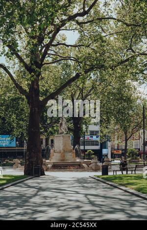 Londres, Royaume-Uni - 13 juin 2020 : peu de personnes se détendent sur un banc devant une fontaine à Leicester Square, l'une des plus populaires et typiquement très bu Banque D'Images