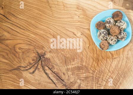 Une portion de boules d'énergie faites maison dans une assiette bleue sur une table en bois texturée. Dessert délicieux et sain. Petit déjeuner. Style de vie. La vue depuis l' Banque D'Images