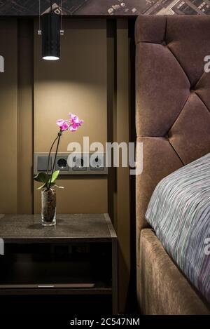 Moscou - 23 mars 2018 : intérieur moderne de chambre d'hôtel ou de maison. Chambre de luxe sombre avec fleurs naturelles sur table de chevet. Chambre interi contemporaine Banque D'Images