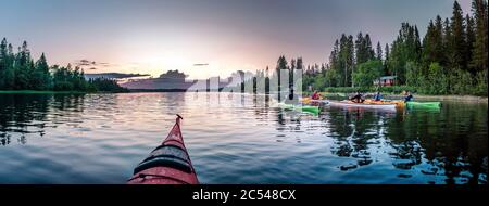 UMEA, SUÈDE - 26 JUIN 2020 : groupe de jeunes pagayant à la lumière de minuit en Laponie suédoise, eau cristalline, soleil de nuit, forêt, cabane rouge Banque D'Images