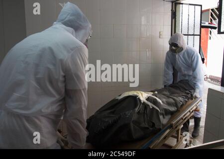 Deux travailleurs de Piedra Angel Crematory, portant des équipements de protection, retirent le corps de Ricardo Medina Sosa (86), qui est mort dans sa propre chambre de t Banque D'Images