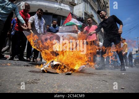 Les manifestants palestiniens brûlent des affiches représentant les visages du président américain Donald Trump, du Premier ministre israélien Benjamin Netanyahou et des drapeaux israéliens, lors d'une manifestation contre les plans israéliens d'annexion de parties de la Cisjordanie occupée. Banque D'Images