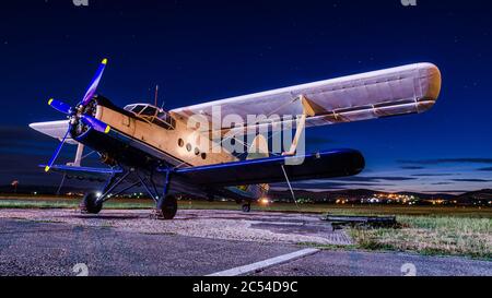 Ancien avion classique vintage sur un petit aérodrome de nuit avec ciel clair. Biplan abandonné en exposition prolongée sous les étoiles Banque D'Images