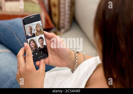 Vidéoconférence avec un groupe de personnes. Jeune femme ayant un chat vidéo avec beaucoup de gens sur son téléphone mobile. Banque D'Images