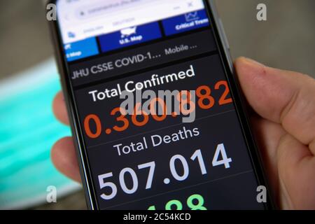 Viersen, Allemagne - juin 30. 2020: Gros plan de l'écran de téléphone portable tenir par main masculine avec le compteur de l'université John Hopkins montrant des nombres de worldwi Banque D'Images