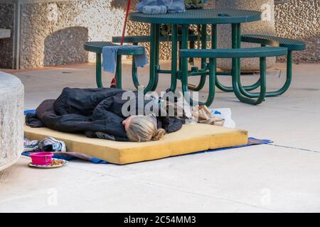 Tucson, AZ - 26 novembre 2019 : personne sans domicile dormant sur une dalle de mousse à El Presidio Plaza, au centre-ville, avec son chien. Banque D'Images