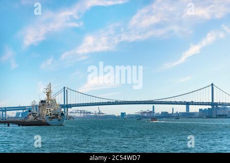 tokyo, japon - avril 04 2020 : bateau amarré sur les rives de la baie de Tokyo, devant le pont Rainbow, avec les grues portiques du Contai International Banque D'Images