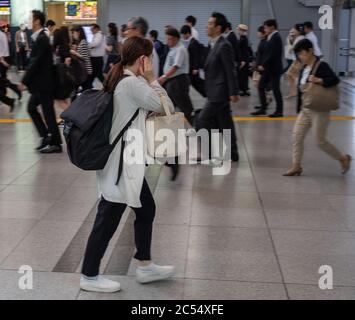 Employés de bureau qui se renaient et marchaient à la gare de Shinagawa, Tokyo, Japon Banque D'Images