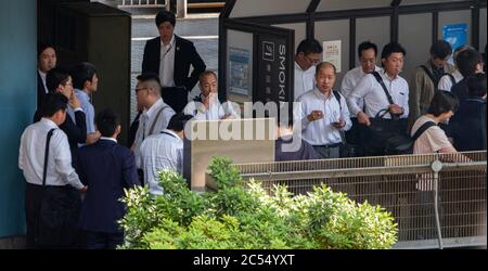 Les personnes qui fument dans un endroit désigné à Shinagawa, Station, Tokyo, Japon Banque D'Images