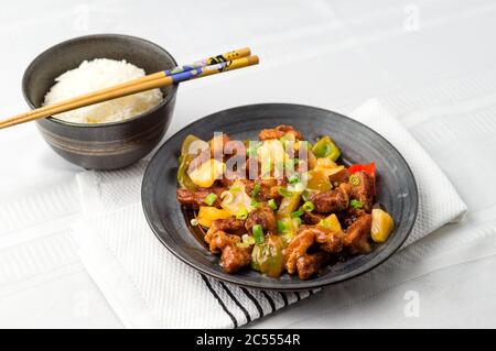 Porc sucré et aigre, cuisine chinoise. La viande frite est ajoutée pour remuer l'ananas, les oignons, les poivrons et la sauce frits. Les plats sucrés et aigre sont courants dans l'asi Banque D'Images