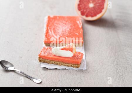 Tarte au pamplemousse sur fond gris. Une tranche de tarte aux fruits a été coupée et est prête à manger. La garniture de pamplemousse rose frais fait TH Banque D'Images