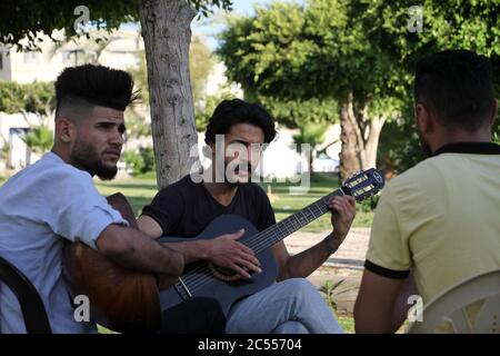 Gaza. 24 juin 2020. Les membres de la bande palestinienne 'Street Band' se sont spectacle dans un parc de la ville de Gaza, le 24 juin 2020. Chaque jour, juste avant le coucher du soleil, trois jeunes Palestiniens de la bande de Gaza, blockée par Israël, jouent gratuitement de la musique dans les lieux publics pour les résidents locaux afin d'atténuer leurs souffrances. Crédit: Rizek Abdeljawad/Xinhua/Alamy Live News Banque D'Images