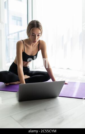 Femme Fitness sélection tutoriel avant l'exercice assis sur le plancher dans la salle de séjour à la maison Banque D'Images