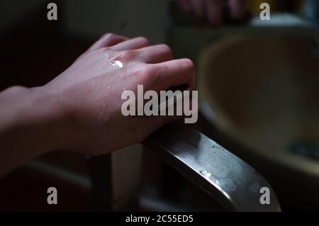 Mains mouillées de femme sur le robinet en métal Banque D'Images