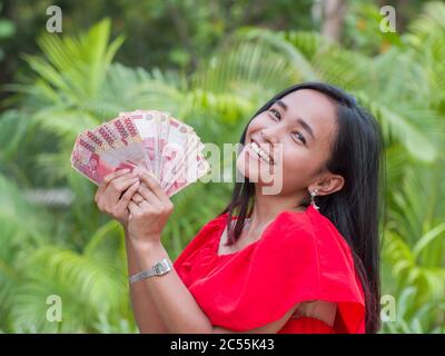 L'argent indonésien entre les mains d'une fille asiatique. Banque D'Images