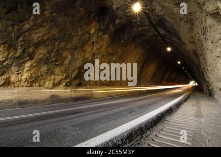 Route dans un tunnel rocheux avec des traces de feux de voiture. Concept de mouvement Banque D'Images