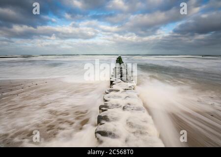 Une plage sur la mer Baltique en hiver, tirant les vagues, la mousse de mer et l'aine menant dans la mer, longue exposition Banque D'Images