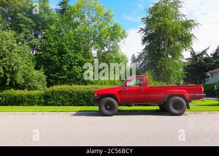 Un vieux camion rouge Toyota stationné dans une rue avec des arbres en arrière-plan. Banque D'Images