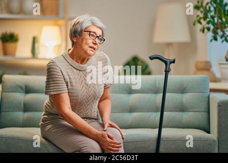 Femme âgée avec canne. Sensation de malaise et douleur au genou. Banque D'Images