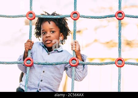 Heureux et beau jeune enfant race noire africaine avec des cheveux alternatifs ethniques jouant dans un terrain de jeu avec des cordes colorées et s'amuser Banque D'Images