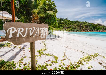 Panneau privé à la plage de sable tropical avec lagon bleu océan en arrière-plan à l'île de Mahé, Seychelles. Banque D'Images