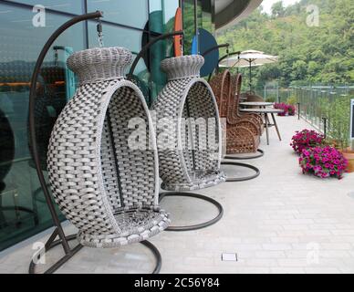 Des fauteuils roulants en osier sont installés sur une terrasse au bord du lac Banque D'Images