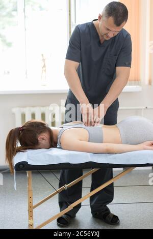 Jeune femme ayant un traitement d'ostéopathie - donnant un massage de dos. Photo intermédiaire Banque D'Images