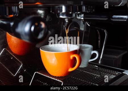 Le café fraîchement préparé est versé de la machine à café dans des tasses . Verser, boisson. Banque D'Images