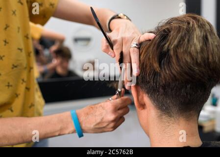 Concept: Unconfinement après le coronavirus, Covid-19. Détail des mains du coiffeur professionnel. Coupe de cheveux pour brunir les cheveux courts femme au coiffeur. Banque D'Images