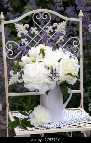bouquet de fleurs de pivoine blanches dans un vase sur une chaise de jardin Banque D'Images