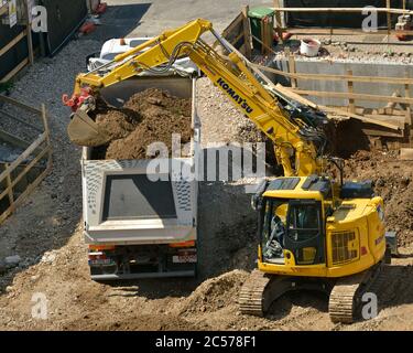 Pelle hydraulique Komatsu creusant les fondations de construction, déchargeant le sol dans un camion-benne Banque D'Images