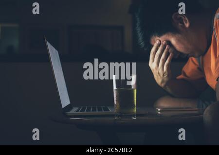 Les hommes boivent de la bière tout en regardant les ordinateurs portables être stressés et tristes. Banque D'Images