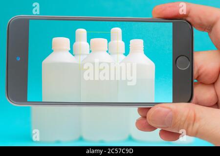 Flacons antiseptiques sur l'écran du smartphone. Liquide désinfectant dans une bouteille blanche. Médicament thérapeutique. Désinfection contre le coronavirus. Banque D'Images